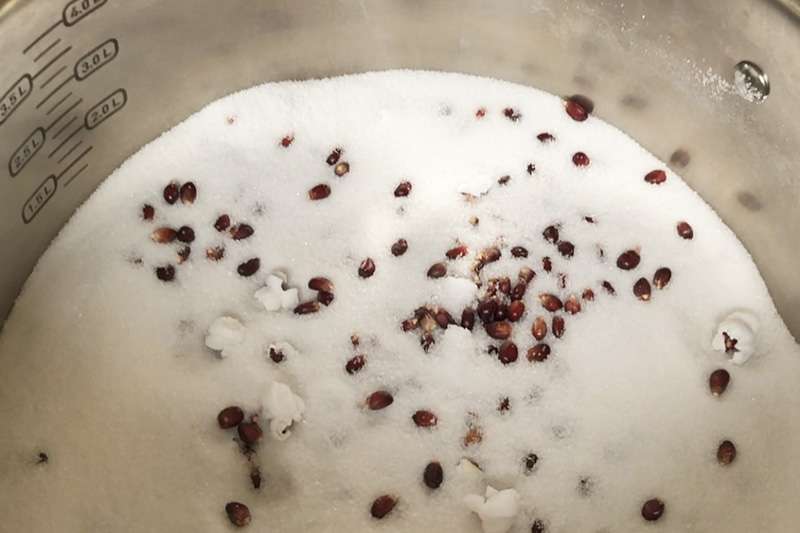 Popcornkärnor poppas i ett tjockt lager salt i kastrull