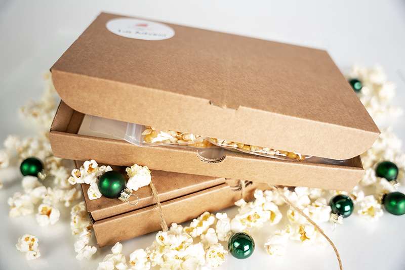 Popcornadventskalender med en låda på glänt. Popcorn och julkulor runt om.
