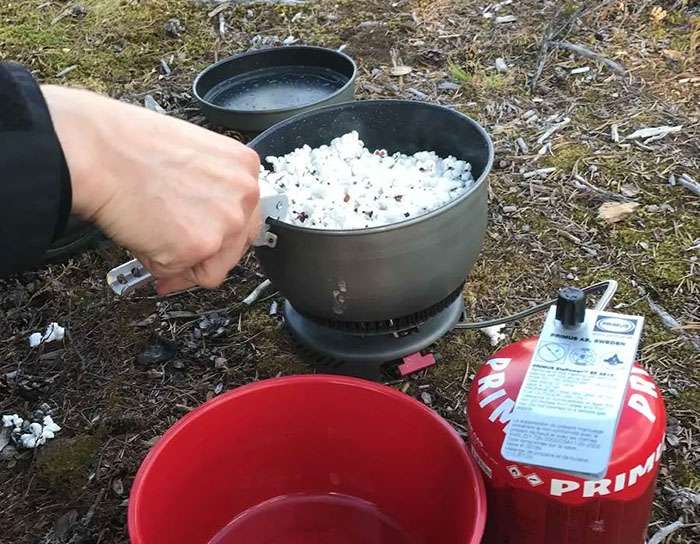 En kastrull med poppade popcorn ovanpå en brännare utomhus