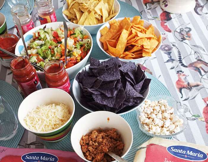 Ett bord uppdukat med olika pålägg till tacos, inklusive en skål popcorn