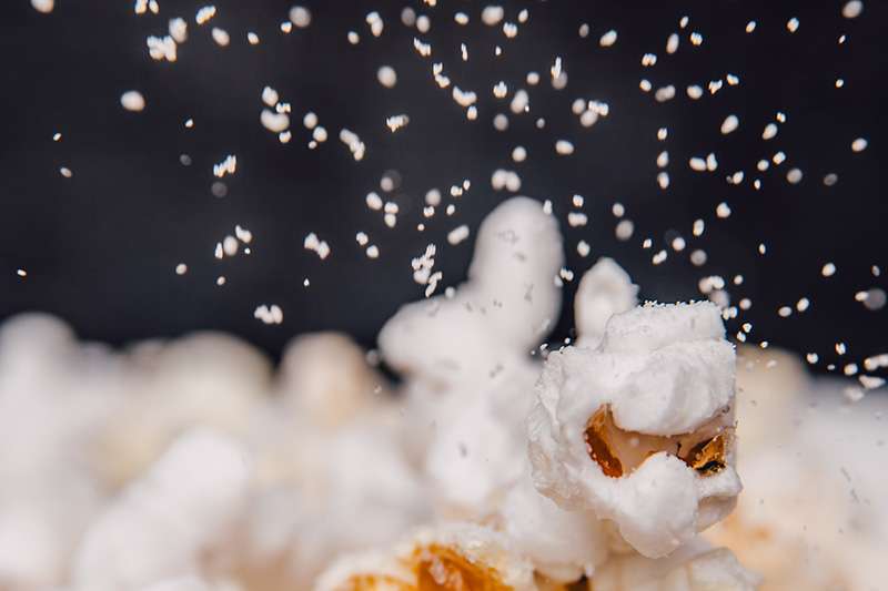 Närbild på salt som strös på popcorn