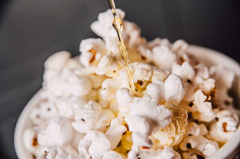 Smält smör som hälls på en liten skål poppade popcorn