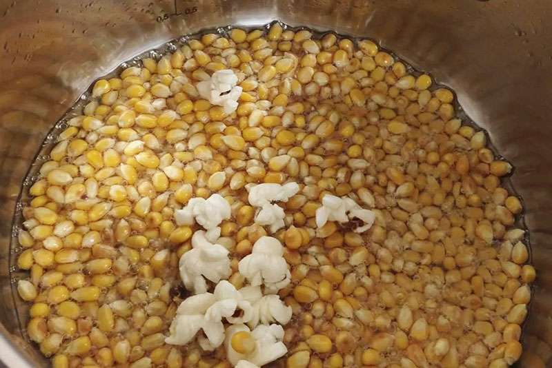 Popcornkärnor i kastrull där de första kärnorna har poppat