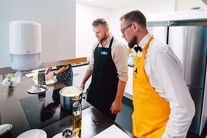 Två personer poppar popcorn vid spisen och håller koll på kastrullen