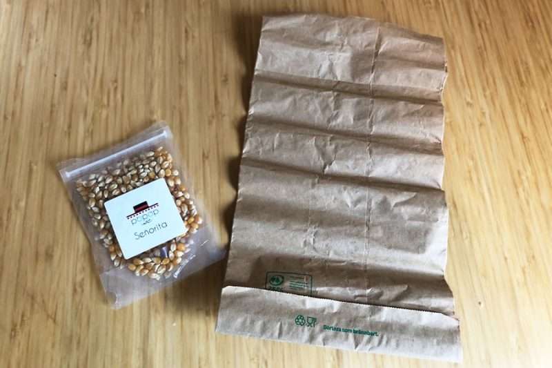 Liten påse popcornkärnor bredvid papperspåse för mikron